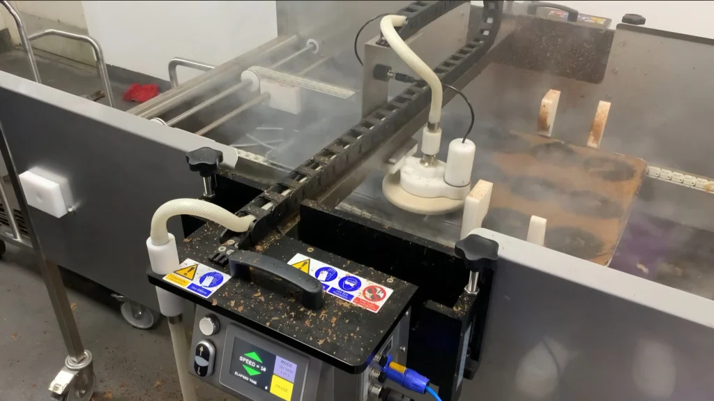 Portable Jet System steam cleaner cleaning bakery pans on a production line using dry vapour steam for chemical-free clean-in-place (CIP) performance.
