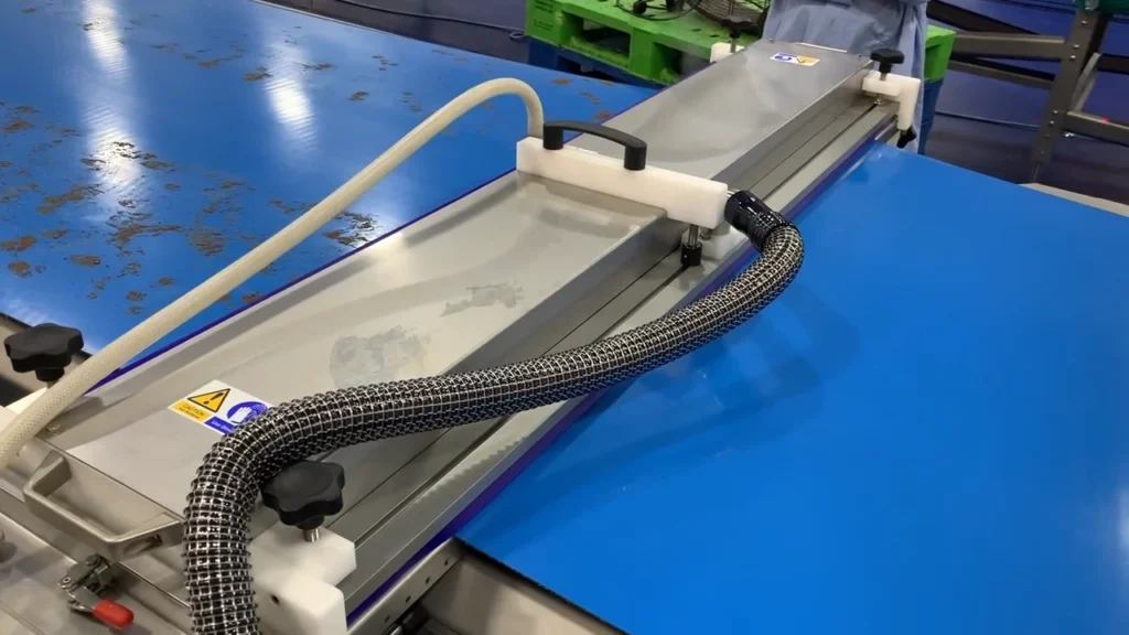 Brushless flat conveyor belt cleaning system using dry steam and vacuum extraction to remove chocolate residue from a blue food-grade conveyor belt.